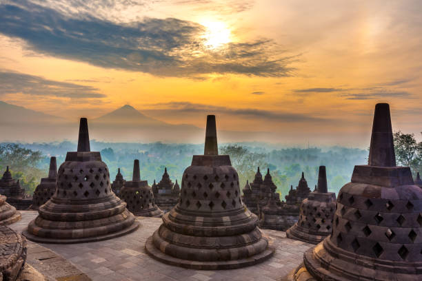 Taman Lumbini park from the height of the temple complex Candi Borobudur at sunrise in the fog.