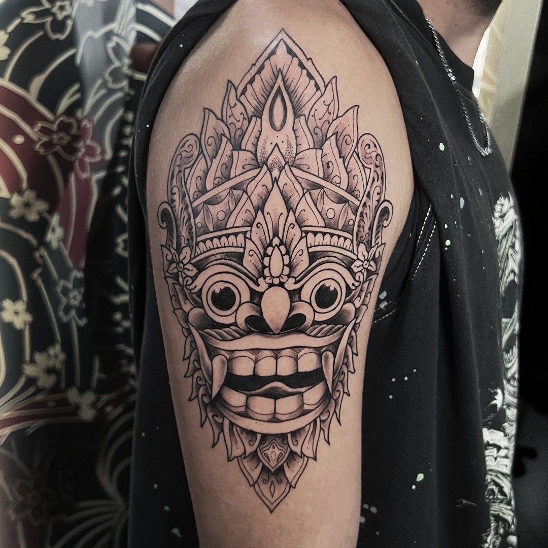 a barong mask tattoo on a man's shoulder
